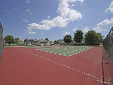 a tennis court with trees and houses in the background