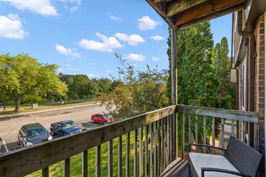a balcony with a table and chairs and cars parked in a parking lot