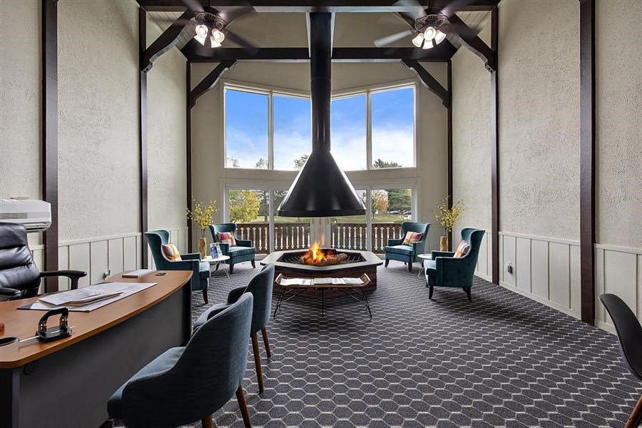a living room with a fireplace and chairs and a table