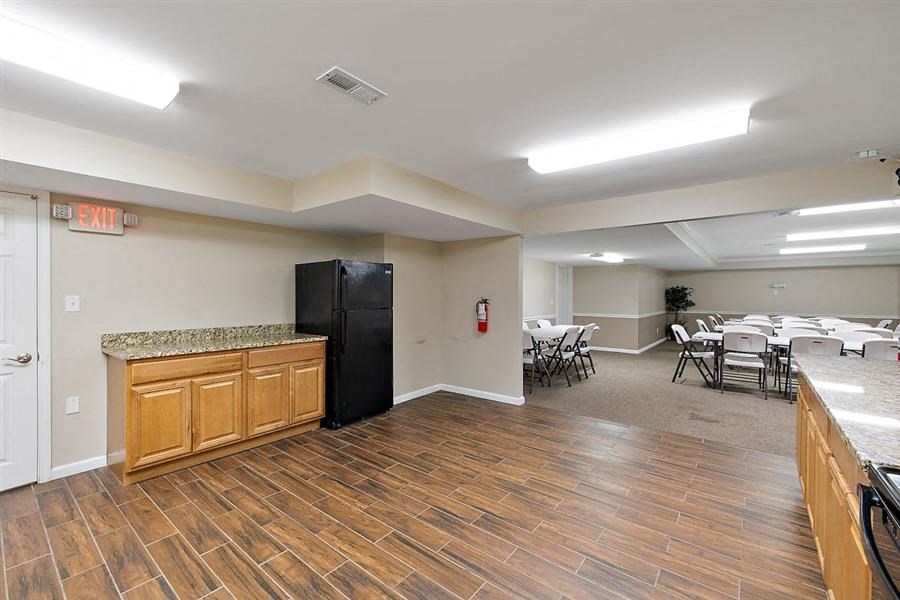 a room with a refrigerator and tables and chairs