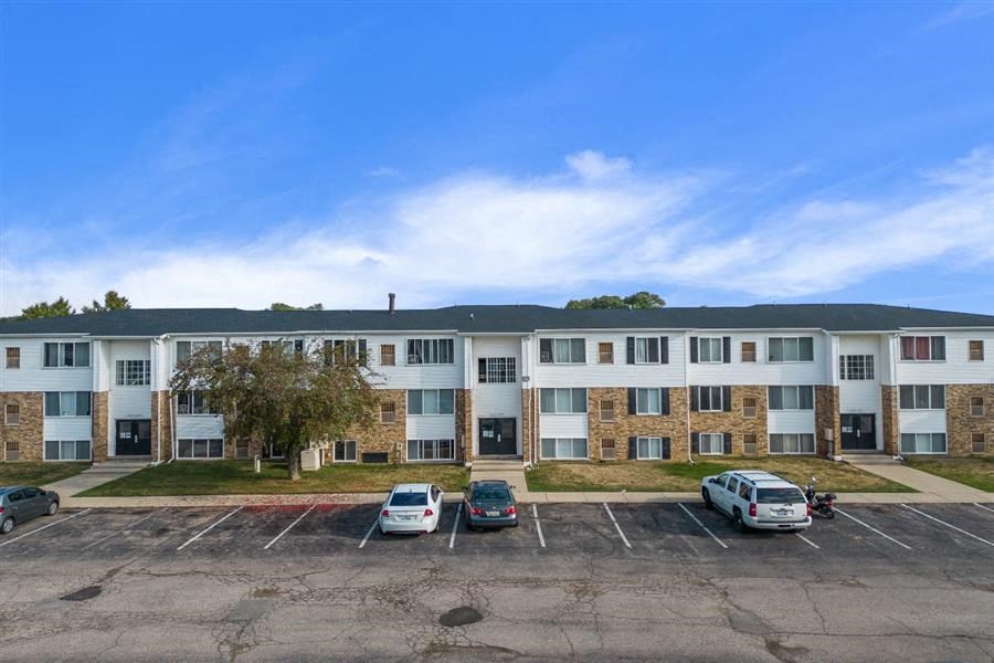 an exterior view of an apartment building with cars in the parking lot