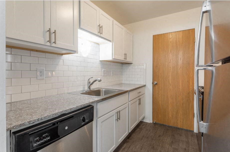 a kitchen with white cabinets and a black dishwasher