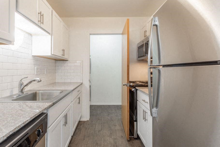 a kitchen with white cabinets and a stainless steel refrigerator
