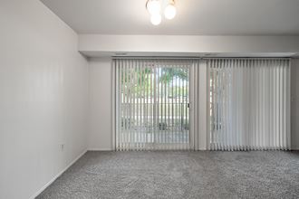 an empty living room with white walls and sliding glass doors