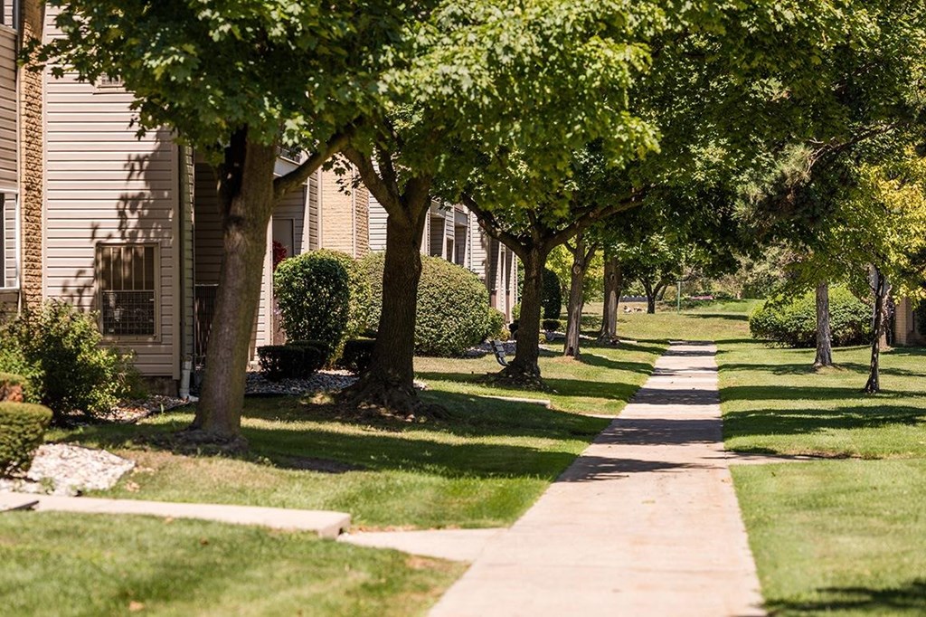 a tree lined sidewalk in front of a house at Sunnymede Apartments - Troy, MI, Troy, Michigan