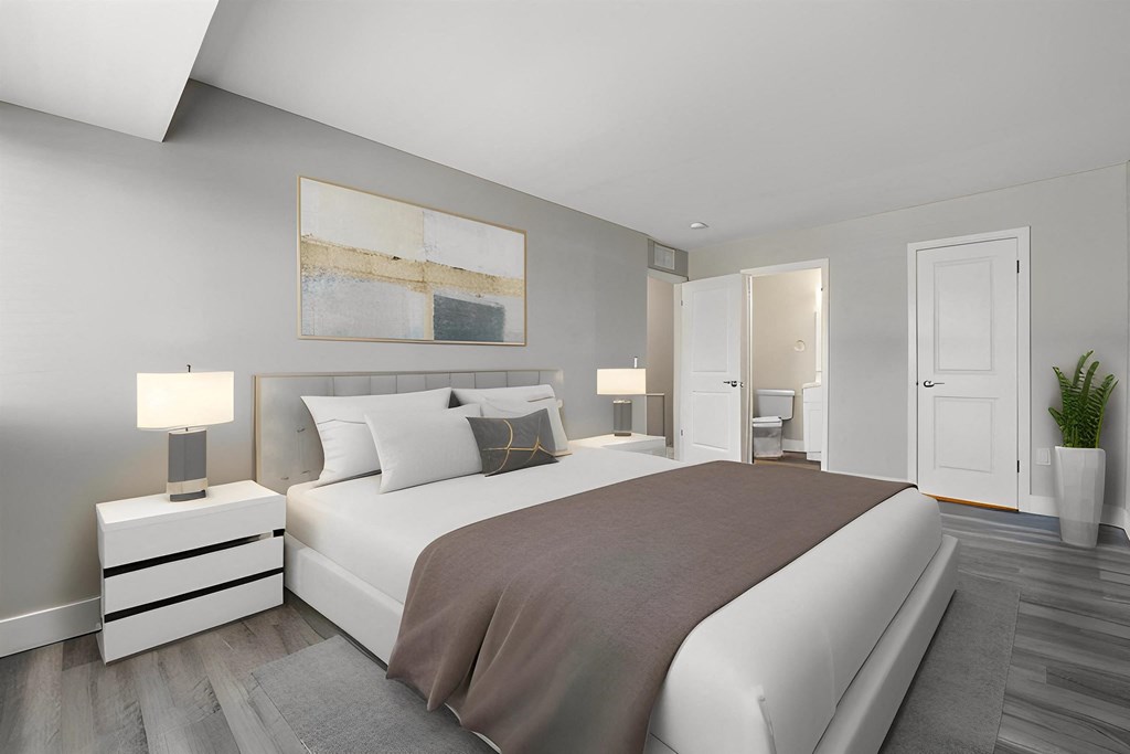 a bedroom with a white bed and a gray blanket at Sunnymede Apartments - Troy, MI, Troy, 48084