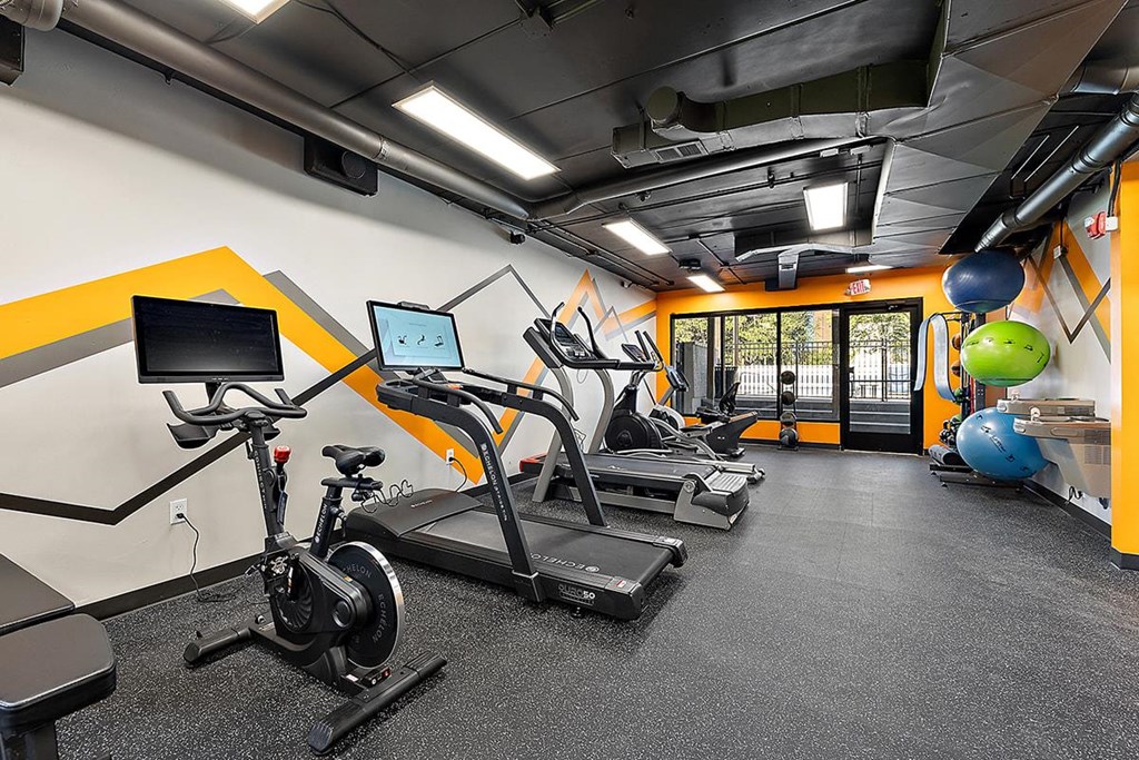 a gym with cardio equipment and weights in a building at Troy Place Apartments - Troy, MI, Troy, Michigan