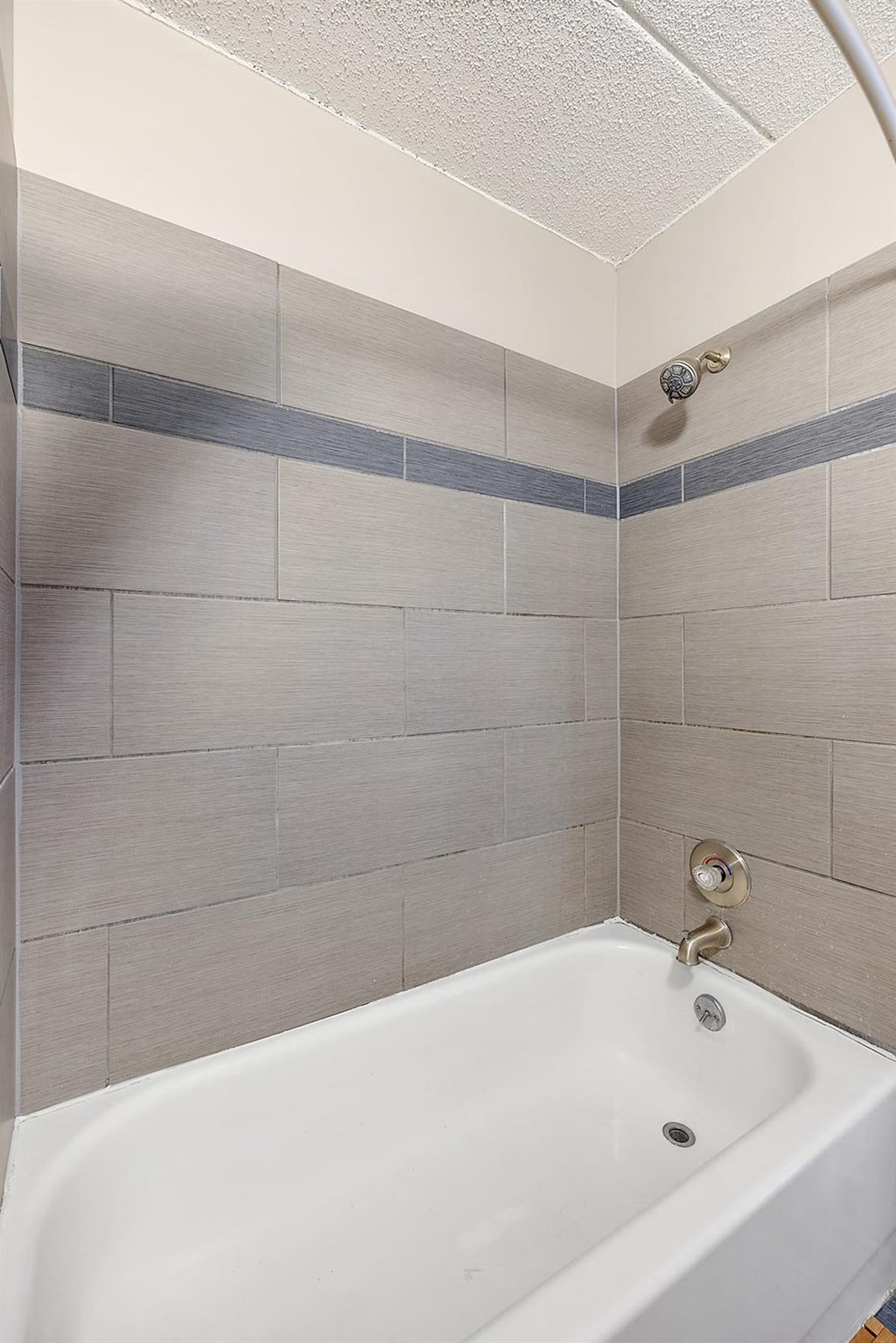 a white bath tub in a bathroom with tile walls at Troy Place Apartments - Troy, MI, Michigan