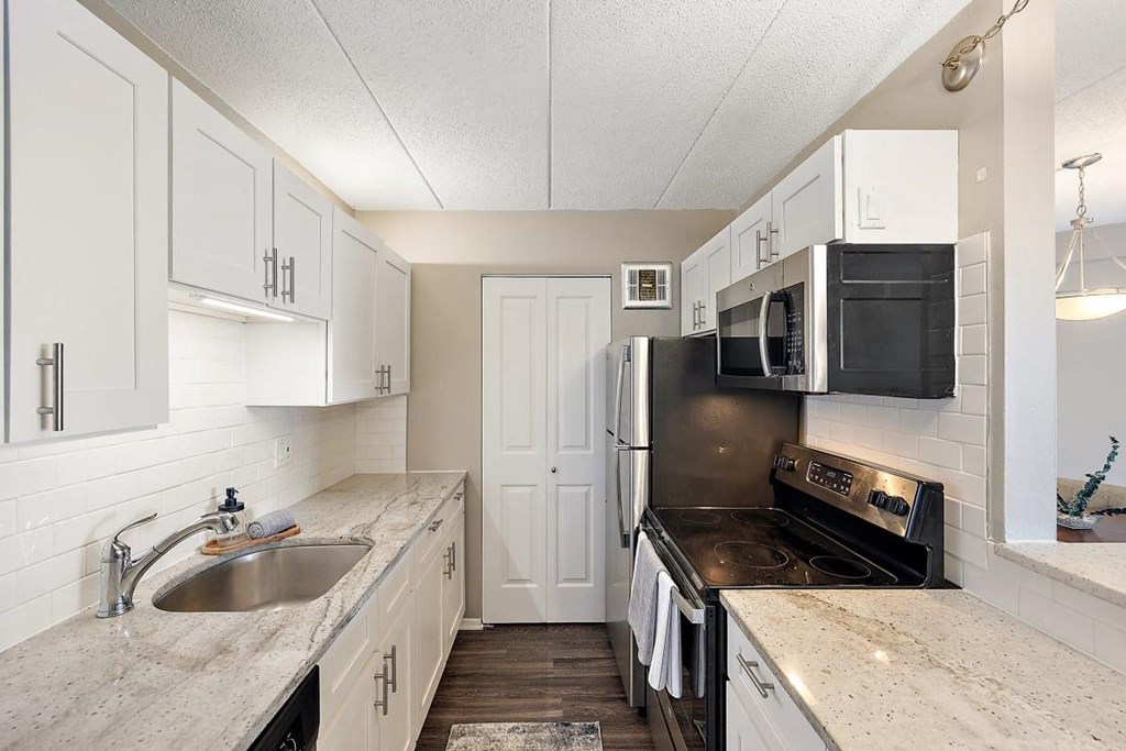 a kitchen with black appliances and white cabinets at Troy Place Apartments - Troy, MI, Troy, Michigan