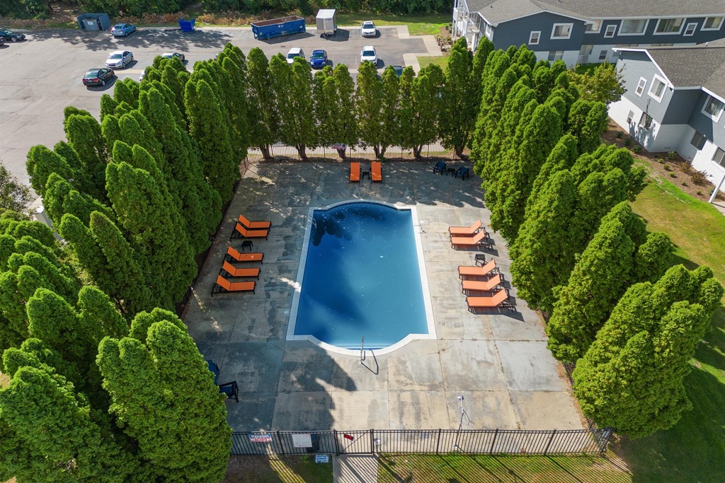 an aerial view of a swimming pool surrounded by trees at Town & Country Apartments - Wixom, MI, Wixom, 48393