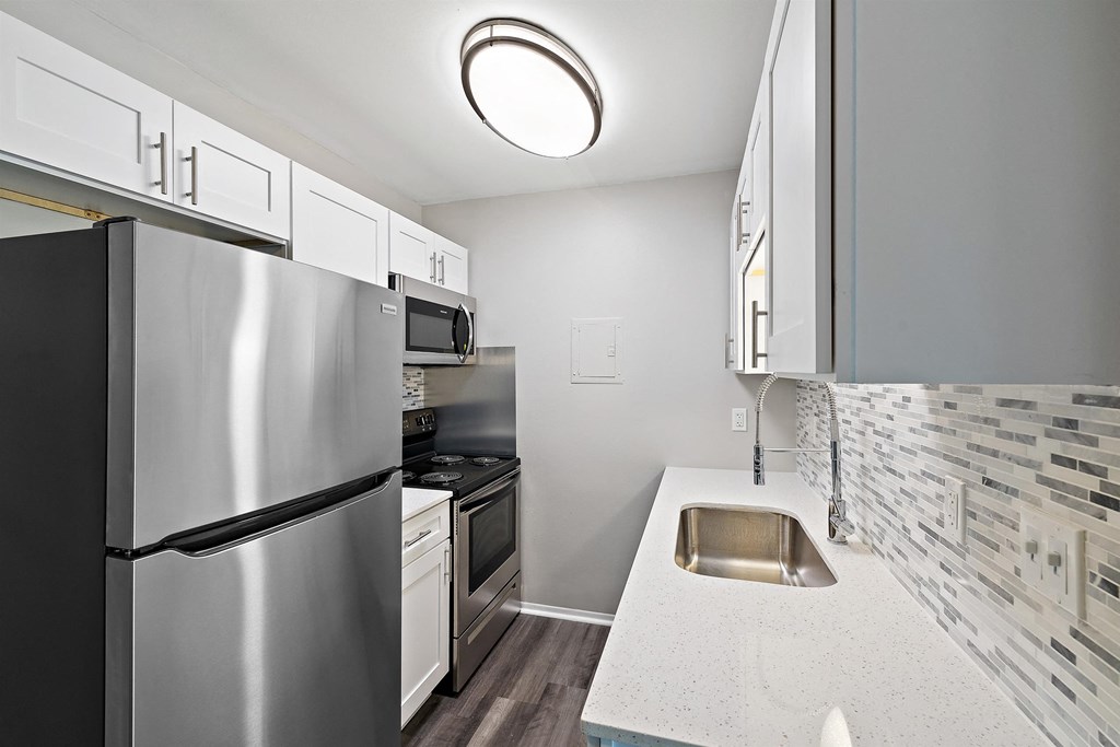 a kitchen with stainless steel appliances and white counter tops at Town & Country Apartments - Wixom, MI, Wixom, Michigan