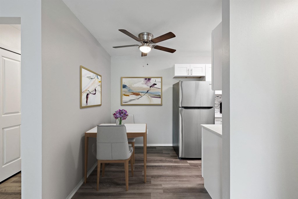 dining room with a table and chairs and a kitchen with a refrigerator at Town & Country Apartments - Wixom, MI, Wixom, 48393