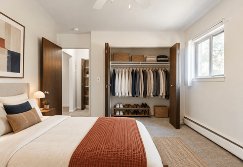 A bedroom with a large bed and a closet with clothes.