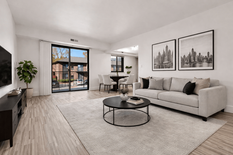 A living room with a grey couch, a coffee table, and two framed pictures on the wall.