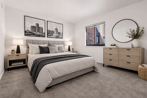 A bedroom with a large bed, a nightstand with a lamp, and a framed picture on the wall.