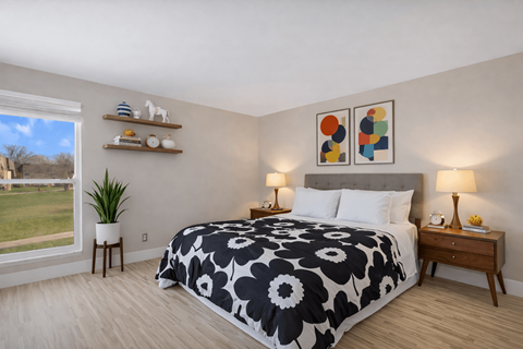 A bedroom with a large bed and a view of a grassy area outside the window. at Rochester Club Apartments, Rochester, 48306