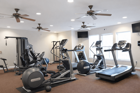 A spacious gym with a variety of equipment including treadmills, stationary bikes, and weight machines.