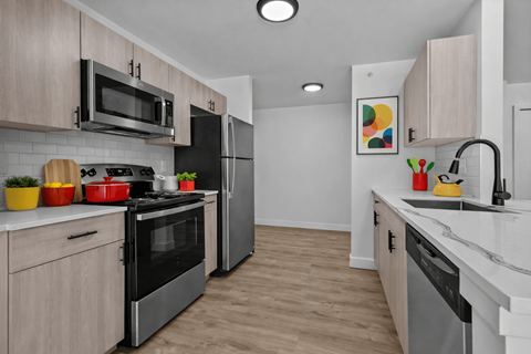 A kitchen with a black refrigerator and stove top oven.