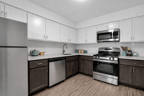 A kitchen with white cabinets and a stainless steel refrigerator.