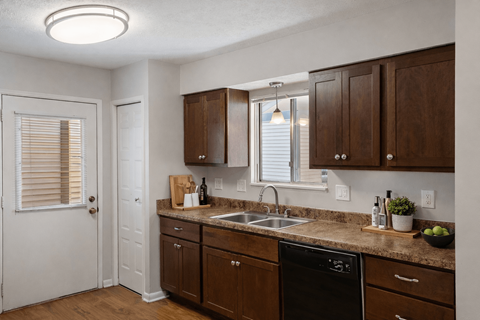 A kitchen with brown cabinets and a black dishwasher.