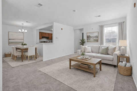 A living room with a white couch, a wooden coffee table, and a dining table with chairs.
