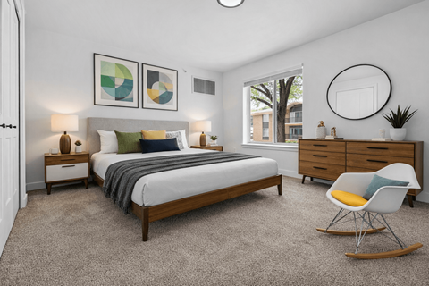 A bedroom with a bed, nightstands, and a chair.