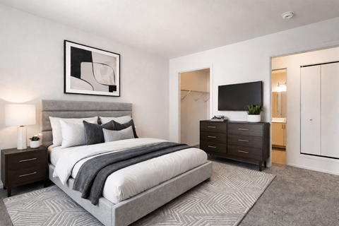 A modern bedroom with a large bed, a nightstand, and a TV.
