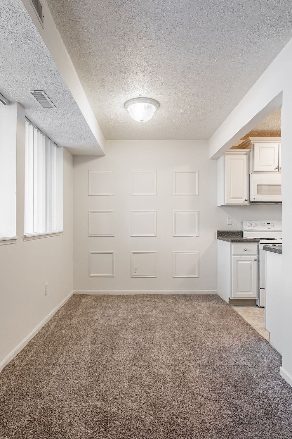 an empty kitchen and living room with a carpeted floor