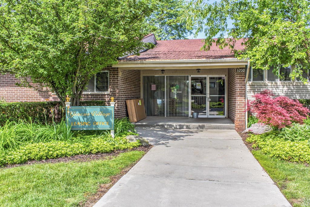the front of a brick building with a sidewalk and a glass door