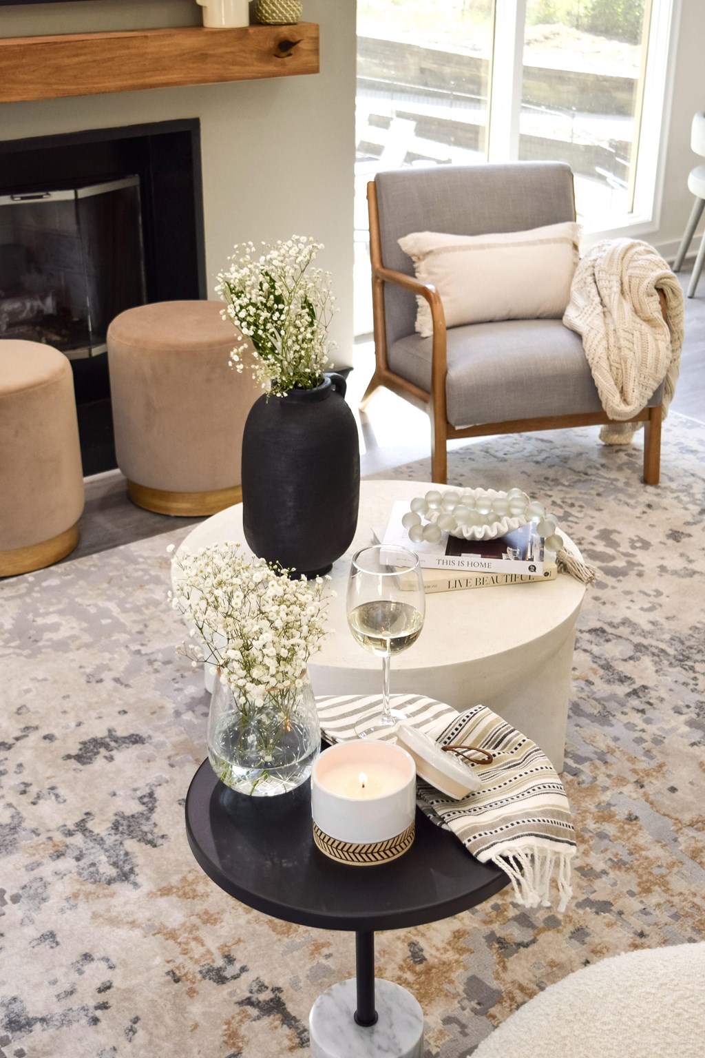 a living room with a coffee table with a vase of flowers and a fireplace