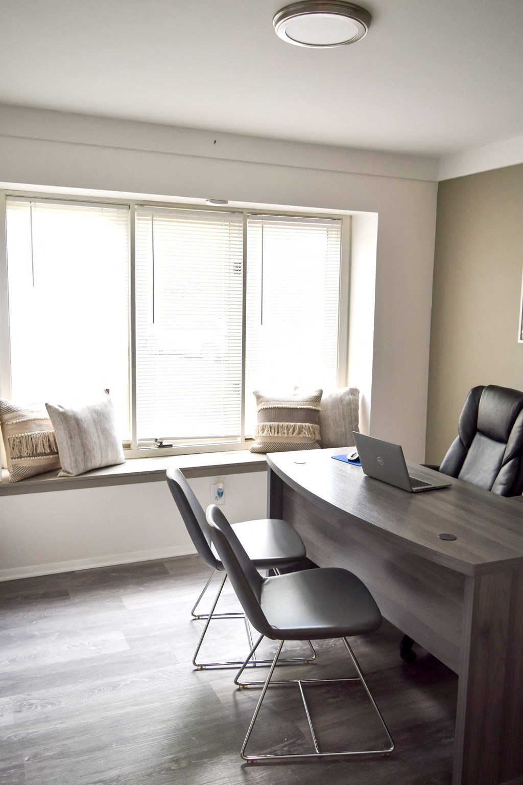 a home office with a desk and chairs and a laptop