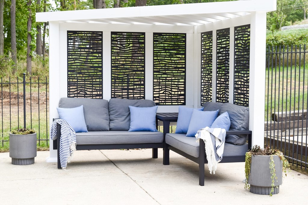 a covered patio with couches and pillows under a pergola