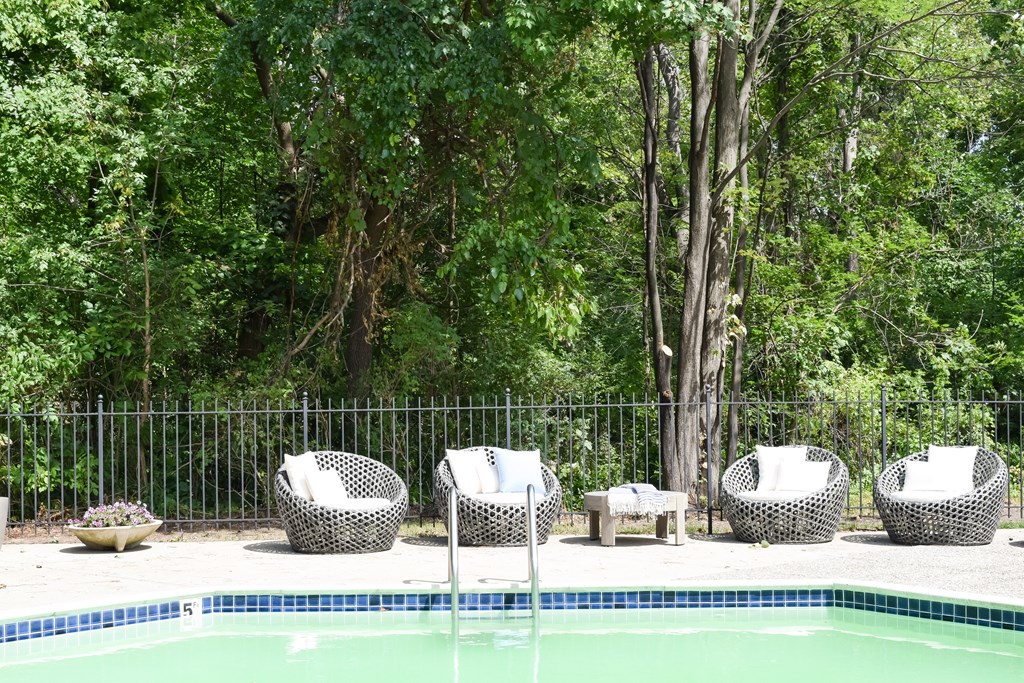 the pool is next to a fence and some chairs