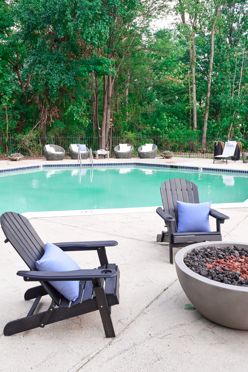 the pool is next to two chairs and a fire pit