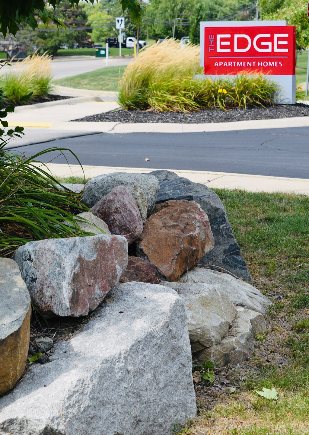 a pile of rocks sitting in the grass in front of a sign