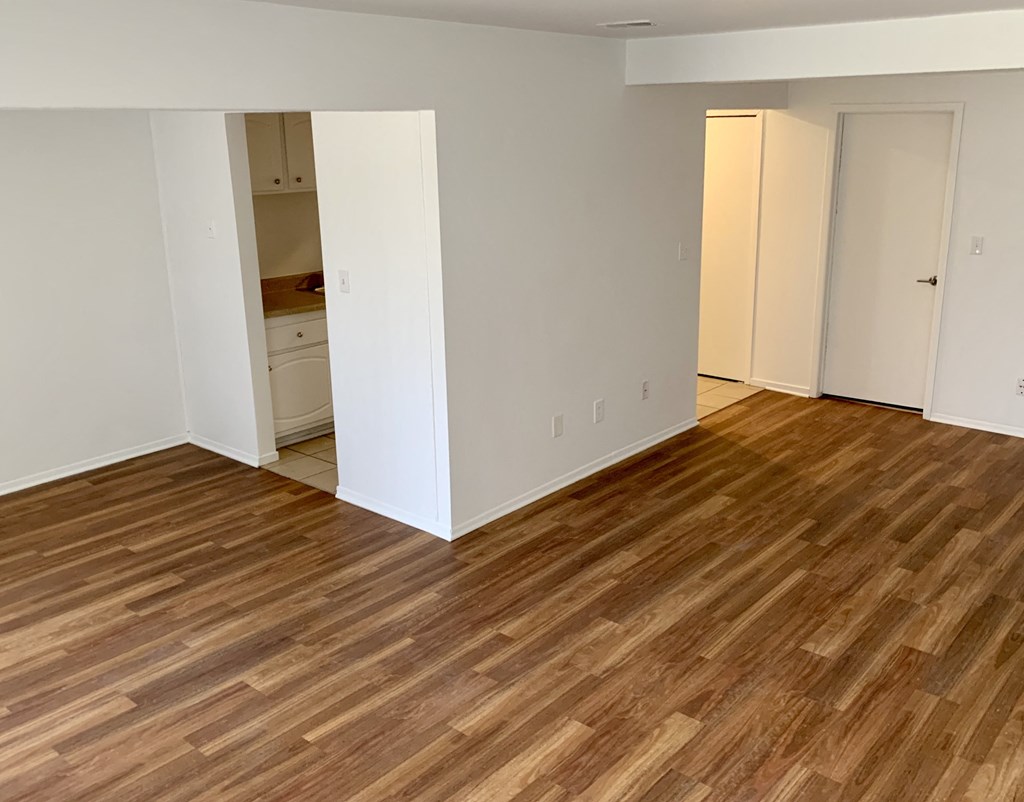 an empty living room with wood flooring and white walls