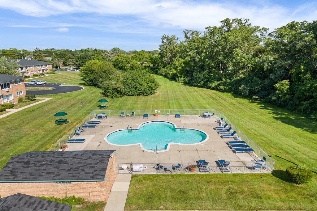 an aerial view of a pool and lawn with chairs around it