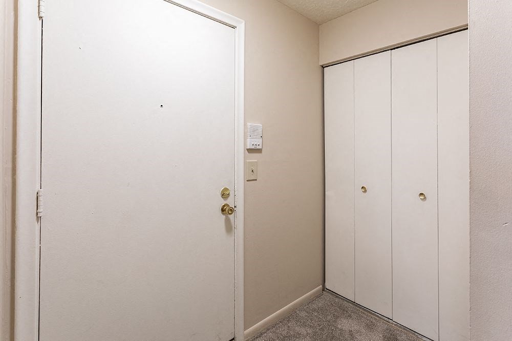 an empty hallway with a door to a closet