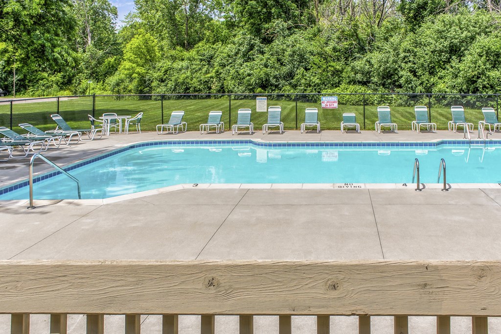 a swimming pool with chairs around it and a wooden fence