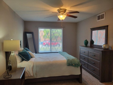A bedroom with a bed, dresser, and window.
