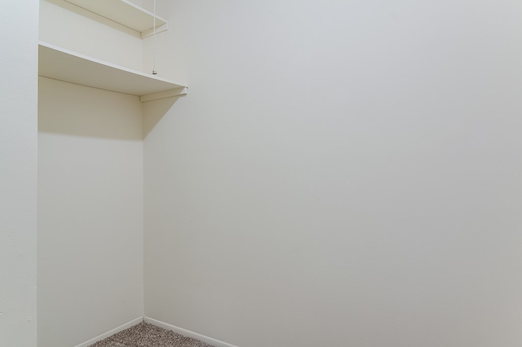 an empty room with white walls and a shelf