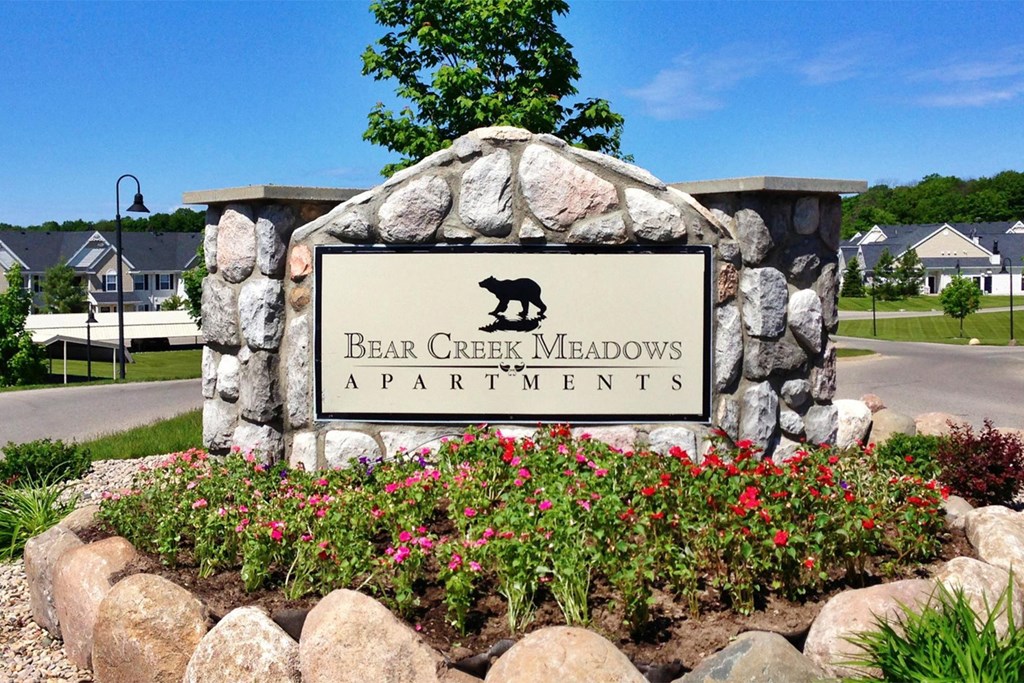 a sign apartments in front of flowers