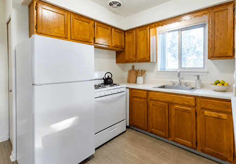 A white refrigerator is in a kitchen with wooden cabinets.