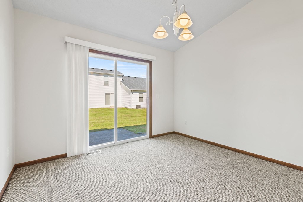 an empty living room with a sliding glass door to a yard