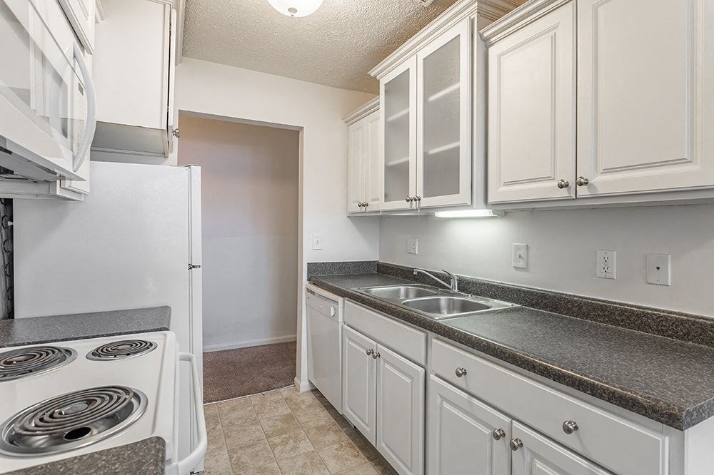 a kitchen with white cabinets and a stove and a sink