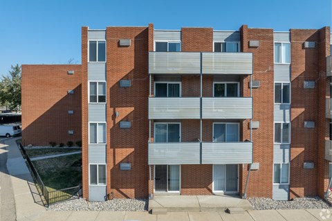 A red brick building with a white van parked in front. at The Park on 13 Apartments - Royal Oak, MI Apartments, Royal Oak