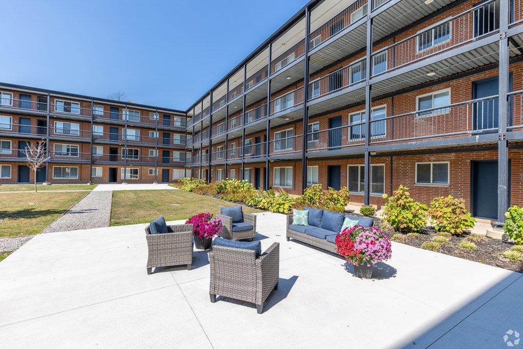 A sunny day at a residential complex with a patio and chairs.