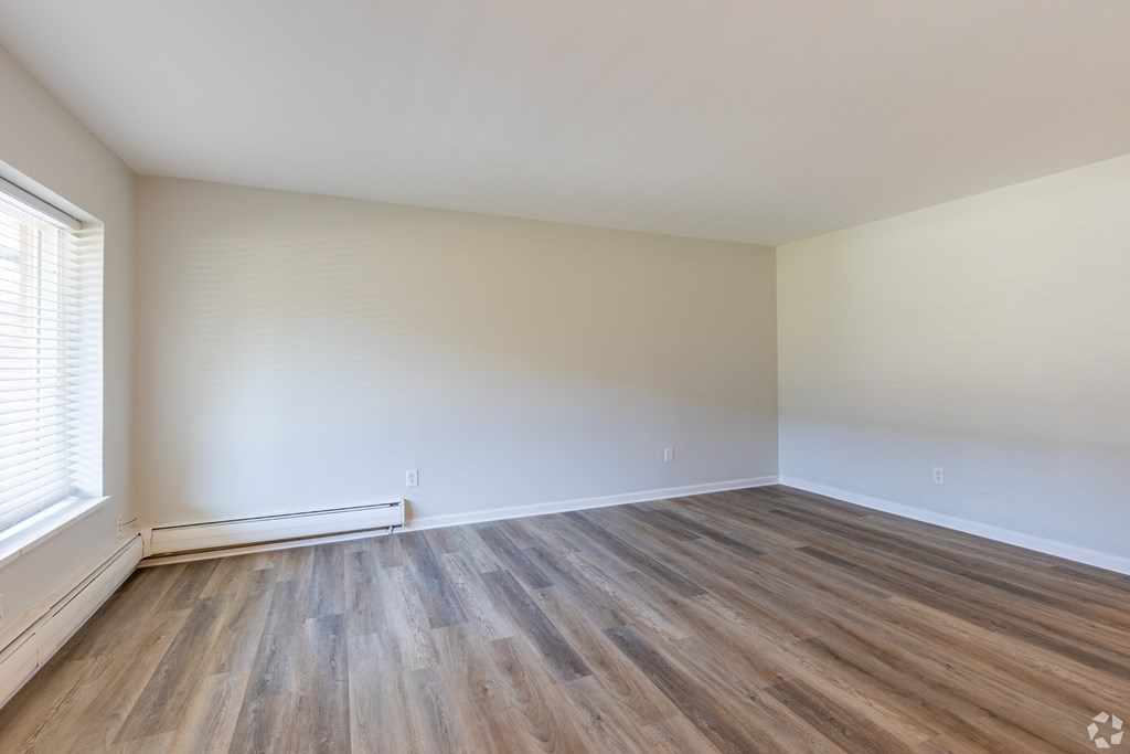 A room with wooden flooring and a window on the left side.