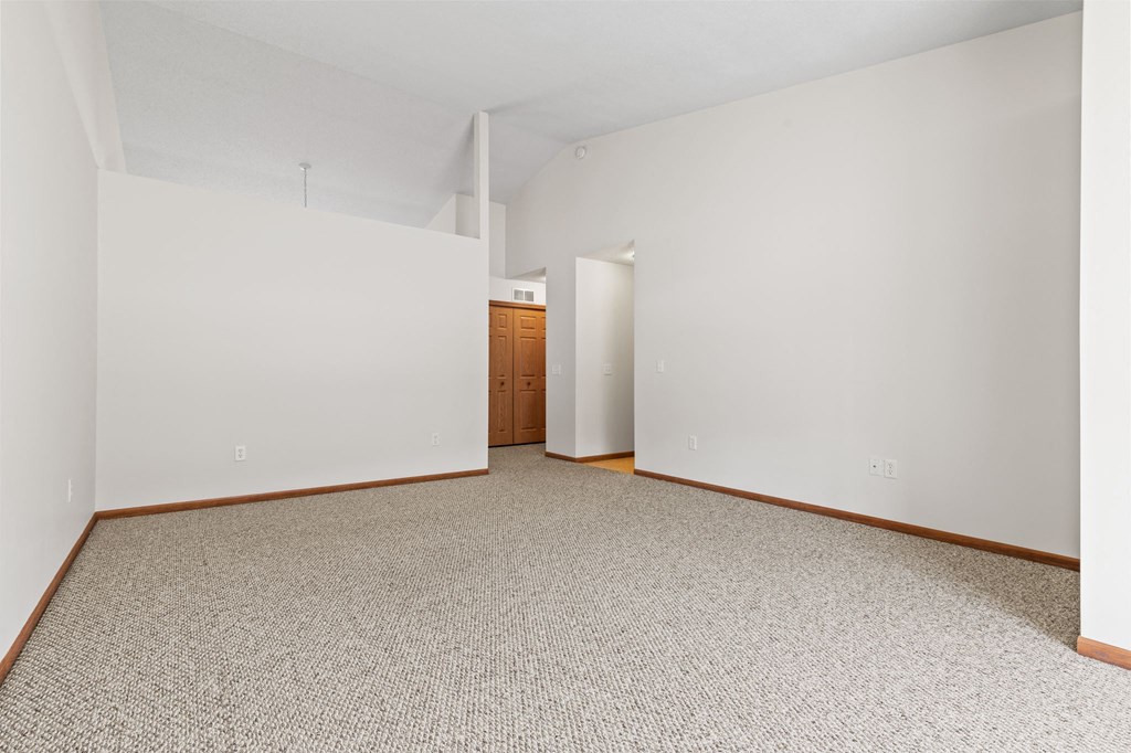a spacious living room with white walls and a carpeted floor