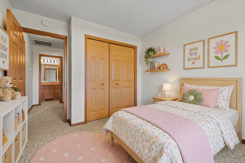 A bedroom with a bed, a dresser, and a shelf with a sign that says "you are loved".